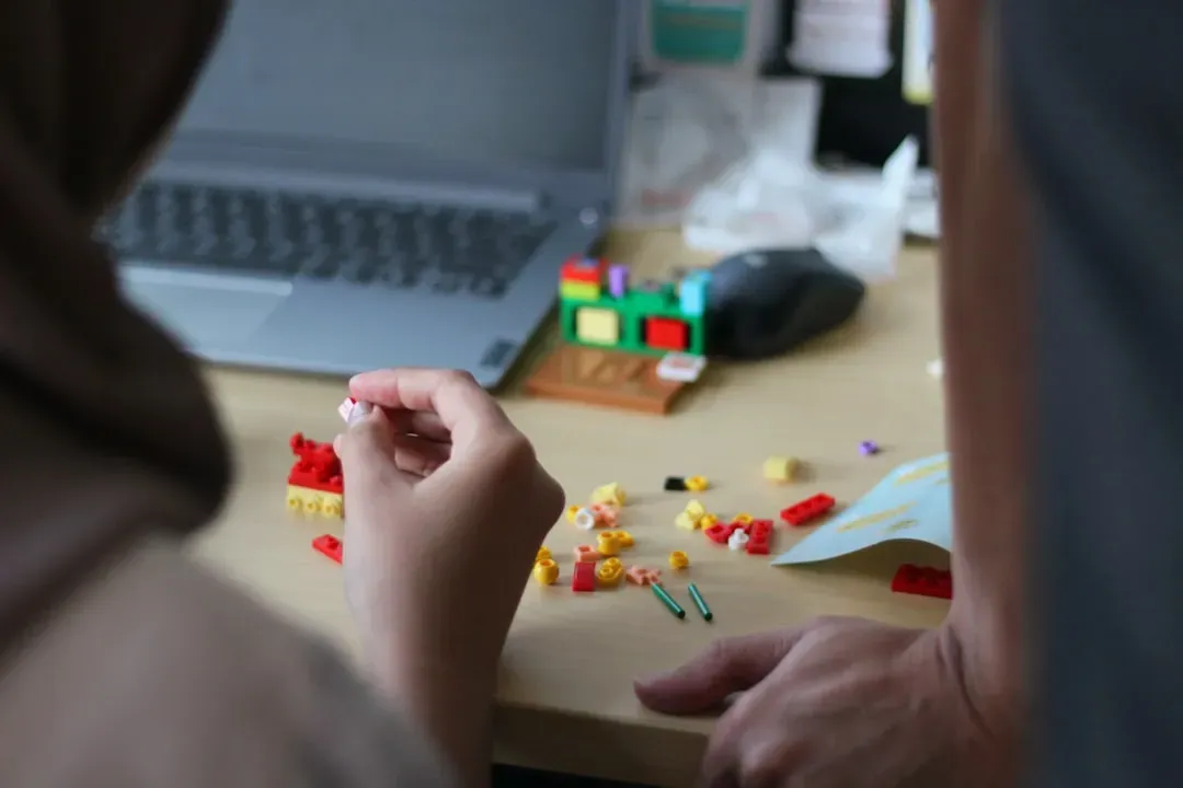 Hands building LEGO Bonsai Tree with instruction booklet visible, showing the meditative construction process step-by-step